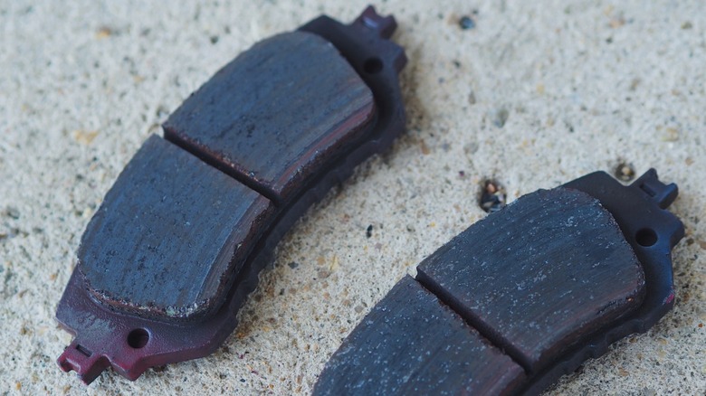 Heated and worn brake pads displayed on a concrete surface
