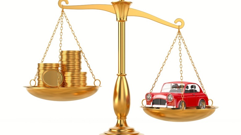 A balance scale holding a stack of coins on one end and a car on the other