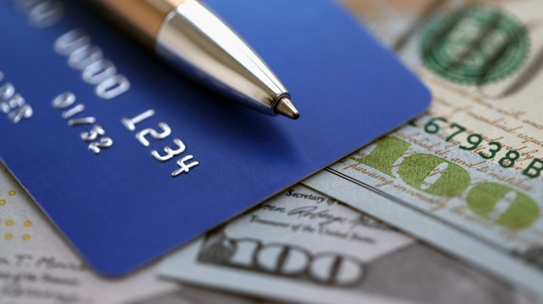 A pen and credit card on top of U.S. currency