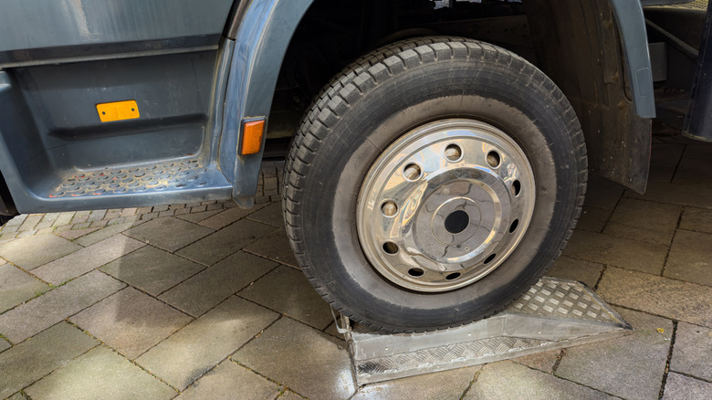 A truck's wheel sitting atop a metal service ramp