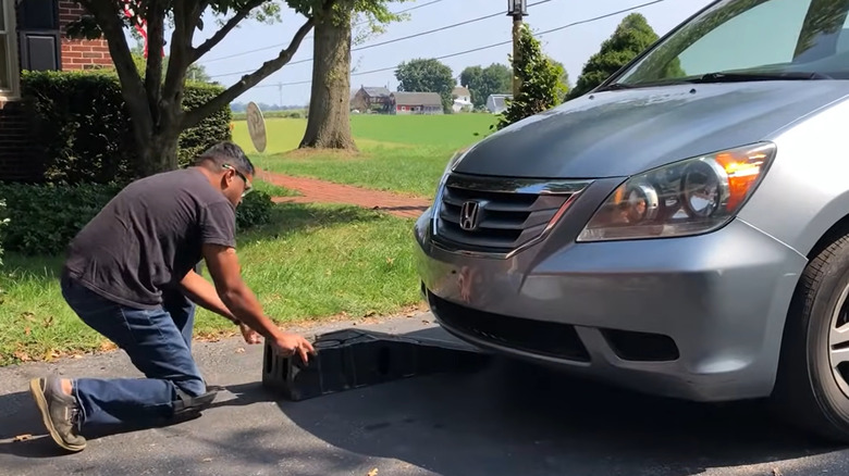 A man moving plastic car ramps into position