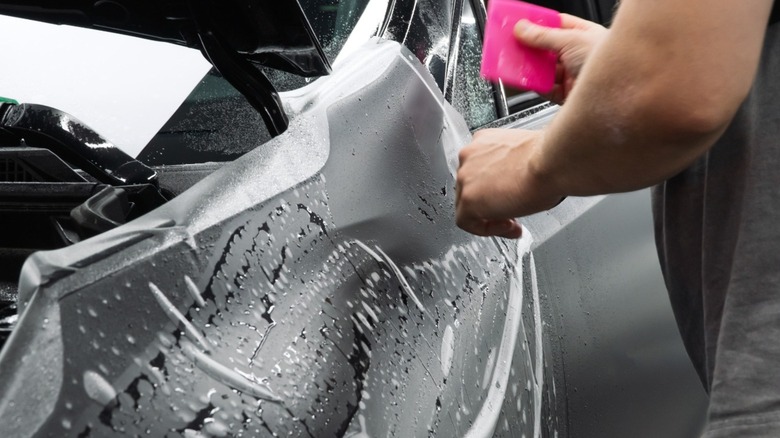 Paint protection film (PPF) being applied to a black car
