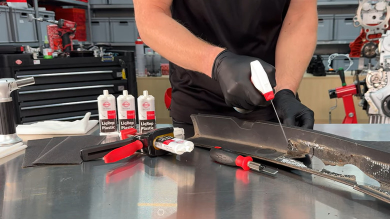 Person preparing surface of car part for application of two-part plastic adhesive