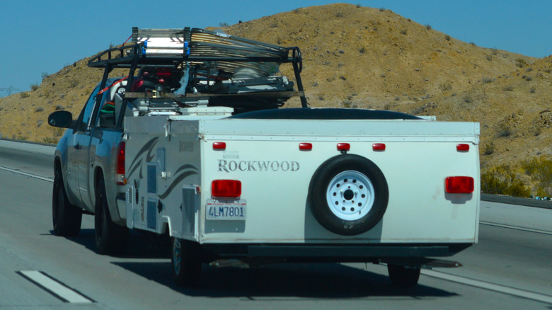 A pickup truck pulling a Rockwood pop-up camper on the highway