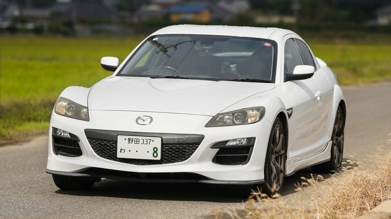 A white Mazda RX-8 driving through the Japanese countryside