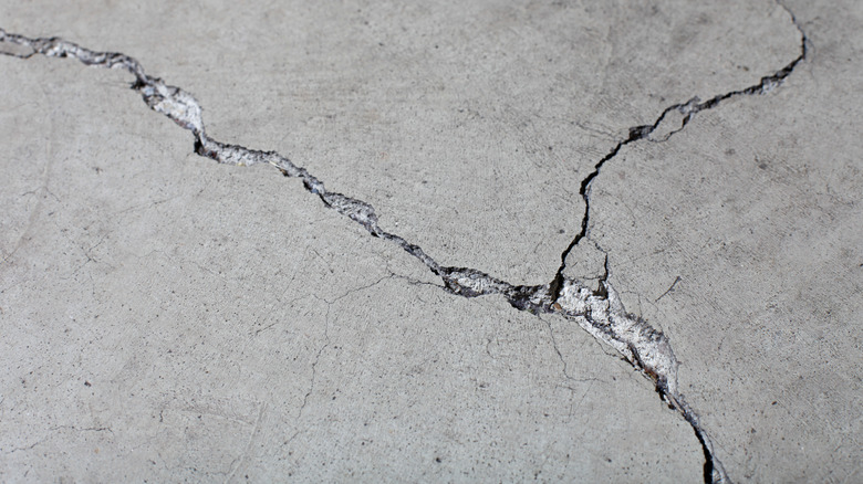 A close-up of concrete slab cracked in an X pattern.