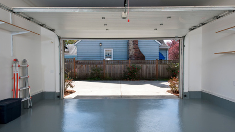 A photo of an interior of a clean garage looking out toward the driveway and the neighbor's house