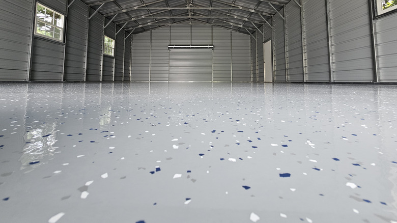 An open space garage with silver doors and a fresh epoxy floor coating.