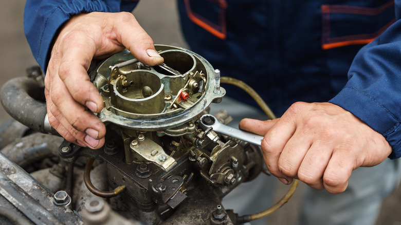 A mechanic fixing a carburetor.