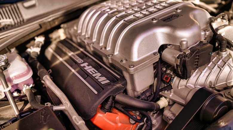 Supercharged hemi v8 engine bay, close-up of high-performance components, belts, wiring and metal details.