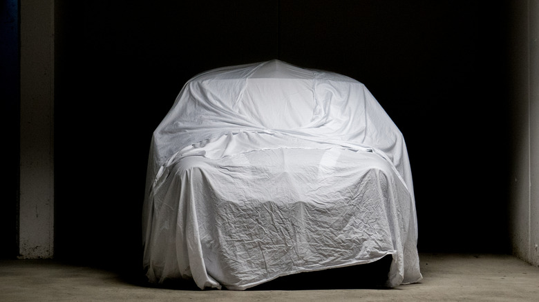 A car underneath a very loose car cover