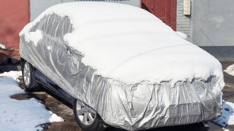 A car in winter, protected by a car cover