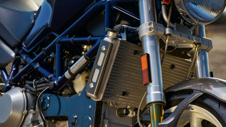 A close-up of a Ducati Monster engine showing the radiator behind the front forks.