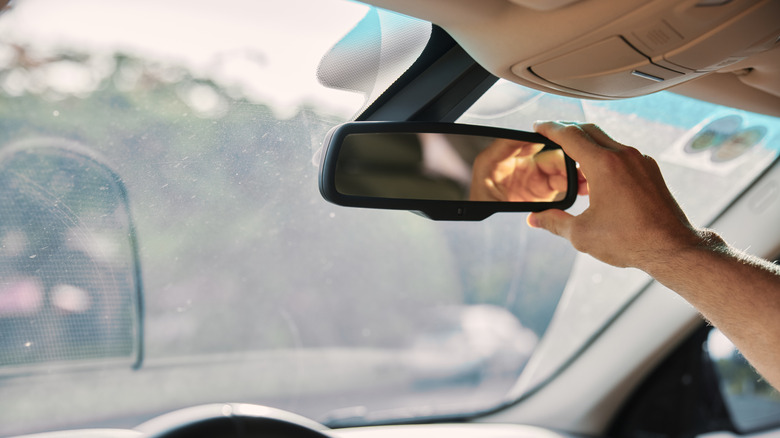 Driver adjusting the rearview mirror