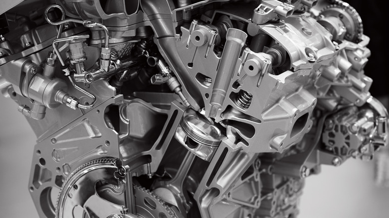 A cutaway image of a car engine, showing the injector and other components