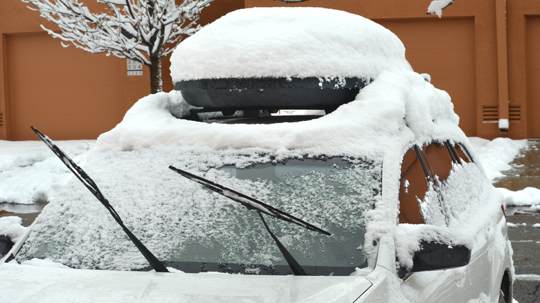 A car with a top carrier and raised wiper blades parked in the snow in New Mexico