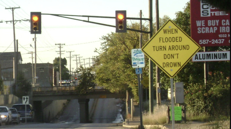 A sign by the side of a road that reads "when flooded, turn around, don't drown."