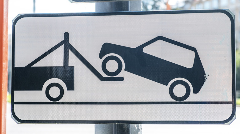 A black and white sign warns drivers of the potential for towing.