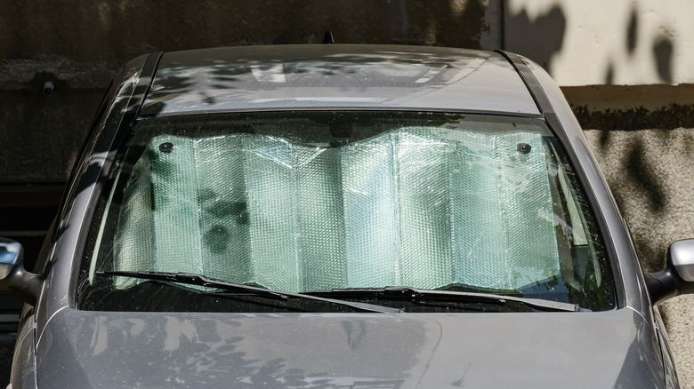 A parked car with a foil sunshade in the windshield to protect against intense heat