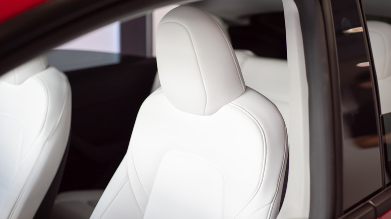 A car cabin with white faux-leather seats
