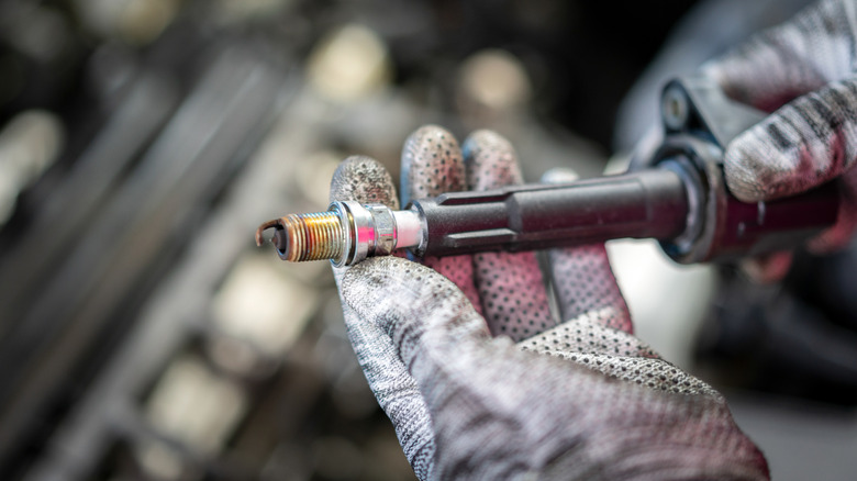 Mechanic holding a spark plug and ignition coil