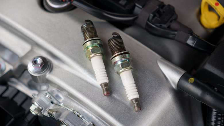 A pair of old spark plugs resting on top of the valve cover