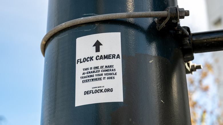 A sign warning drivers and passersby of a Flock camera mounted above