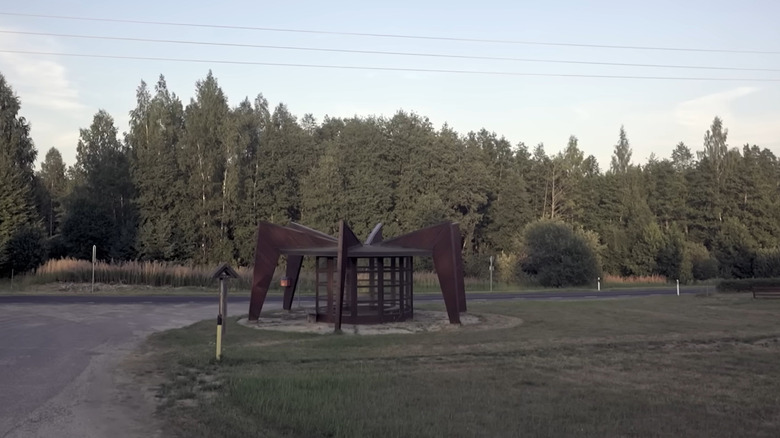 Bus stop that resembles a spider on a quiet road.