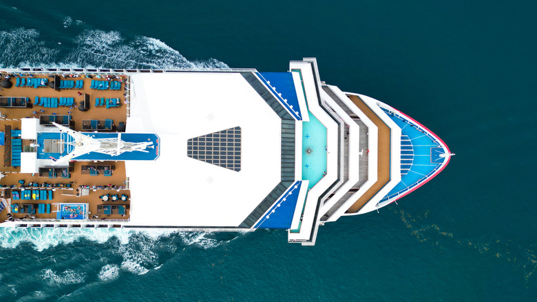 A cruise ship sailing through the ocean as seen from above.