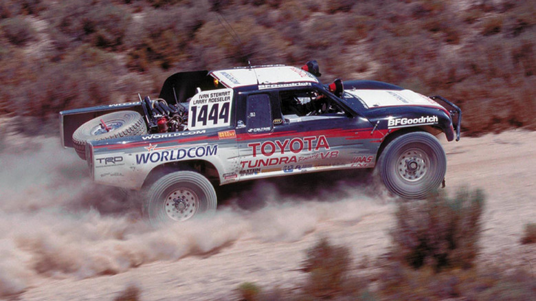 A vintage photo of Ivan Stweart's Toyota V8 desert raving truck driving through the desert kicking up dust