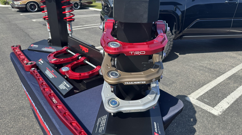 A display table in a parking lot showcasing the red, bronze, and silver upper control arms produced at the TRD facility in Costa Mesa