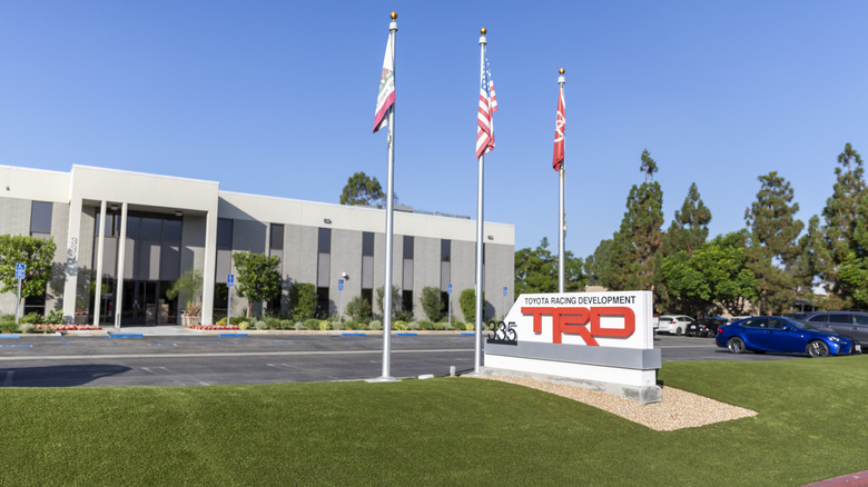 A photo of the TRD headquarters in Costa Mesa showing a TRD sign, three flags, and the building