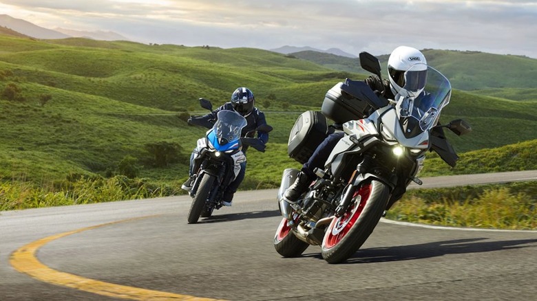 Two Suzuki SV-7GXs going around a corner through grassy hills
