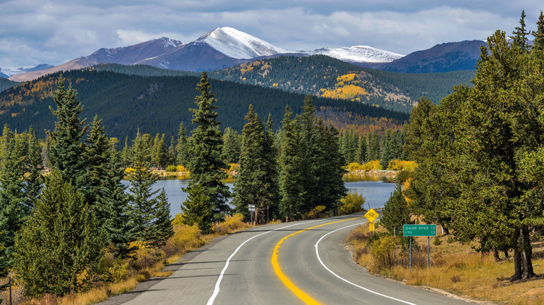 A driver's POV shot of Mount Blue Sky Scenic Byway with a lake and mountains in the background