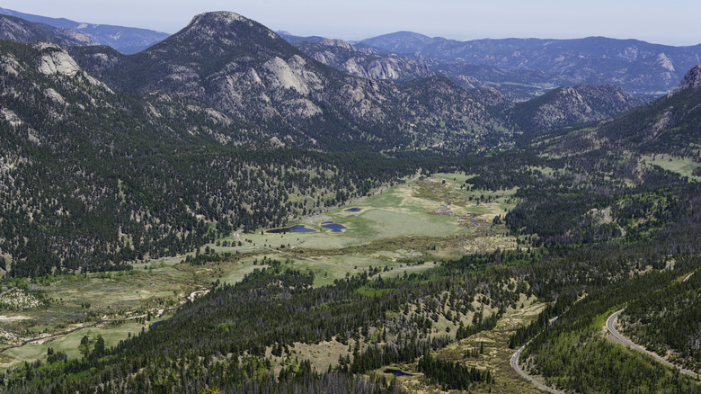 A view from high up on the Trail Ridge Road with fields in the valley and mountains in the distance