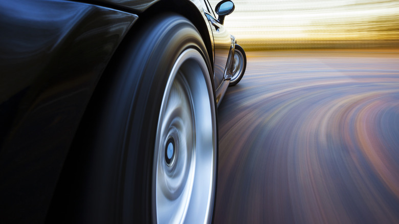 Lower side view of a black sports car turning a corner at high speed
