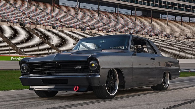 A matte black car parks on a racetrack.