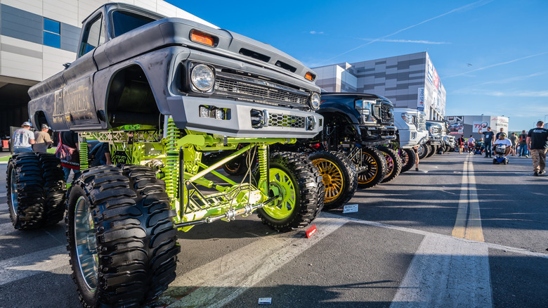 Heavily modified pickup trucks park for display.