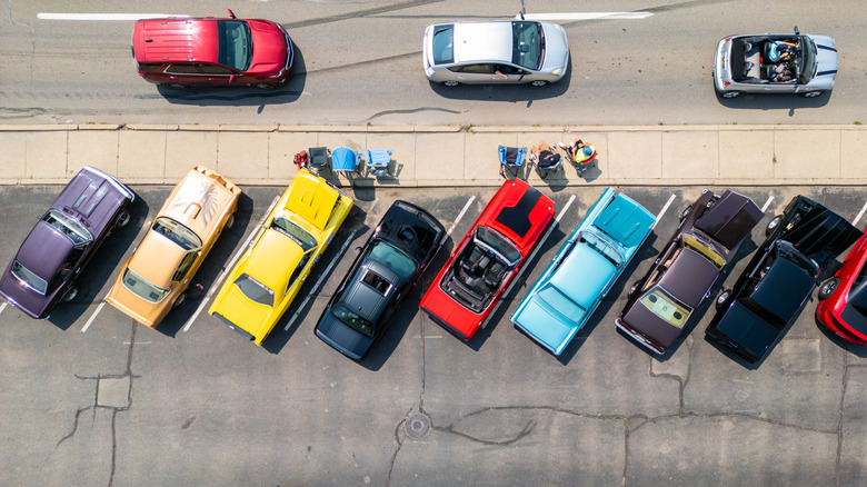 An aerial view shows classic cars parked while others drive on the road.