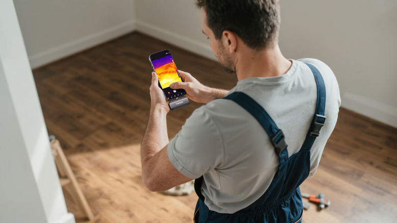 A man uses the TOPDON TC002C Duo to study an under-floor heating system