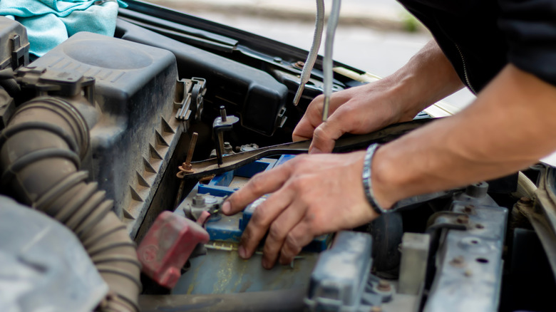 A close-up of a person working within a car's engine bay.