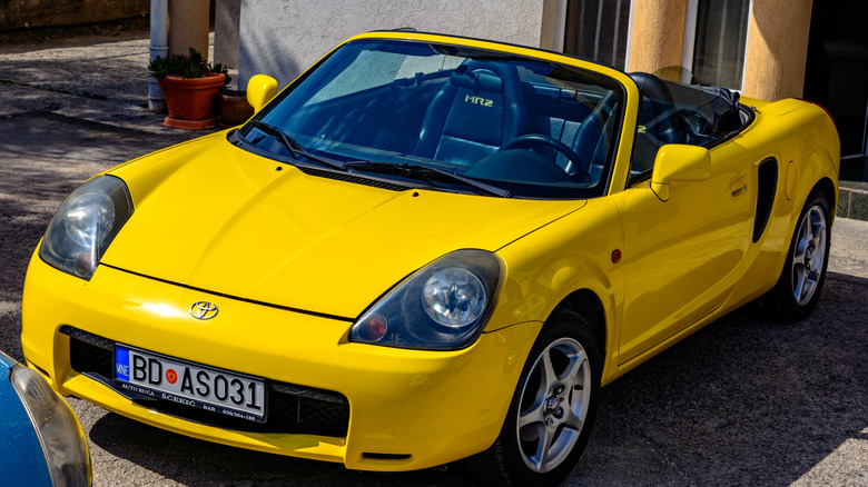 A yelllow Toyota MR2 parked outside