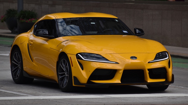 A yellow Mk5 Toyota Supra 2.0 parked on the street.