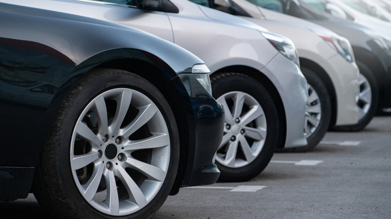 A row of cars for sale including a BMW sedan and a Toyota Prius