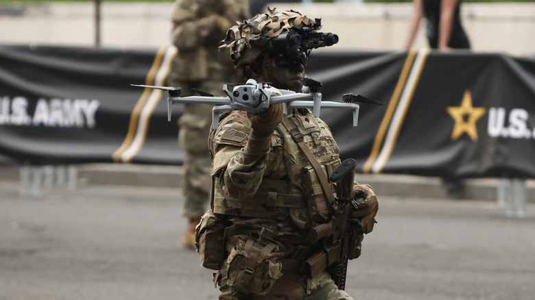 A soldier in camo paint holds a drone