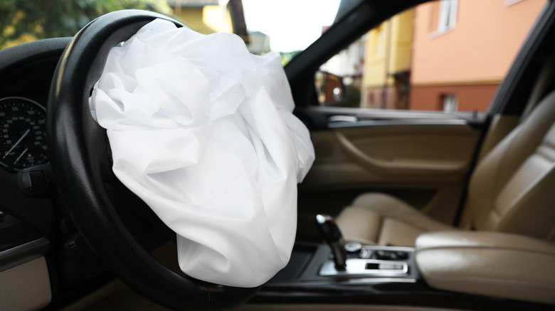An airbag is deployed in a black and tan car interior. No other airbags have been deployed.
