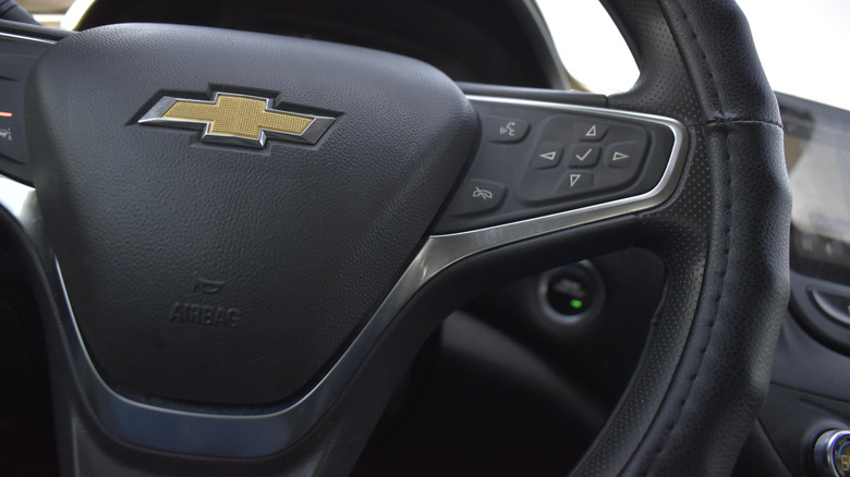 Close-up crop of a black Chevrolet steering wheel of the similar year Malibus involved in the NHTSA findings.