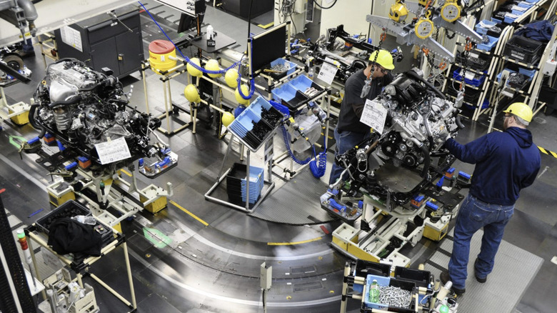 People work on an engine on a Toyota assembly line.