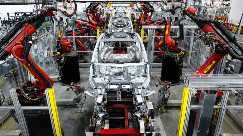 A vehicle is assembled with robot arms in a Tesla factory.