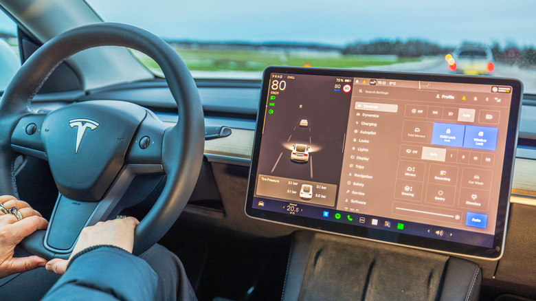 A person driving a modern Tesla with all the controls available via a touchscreen